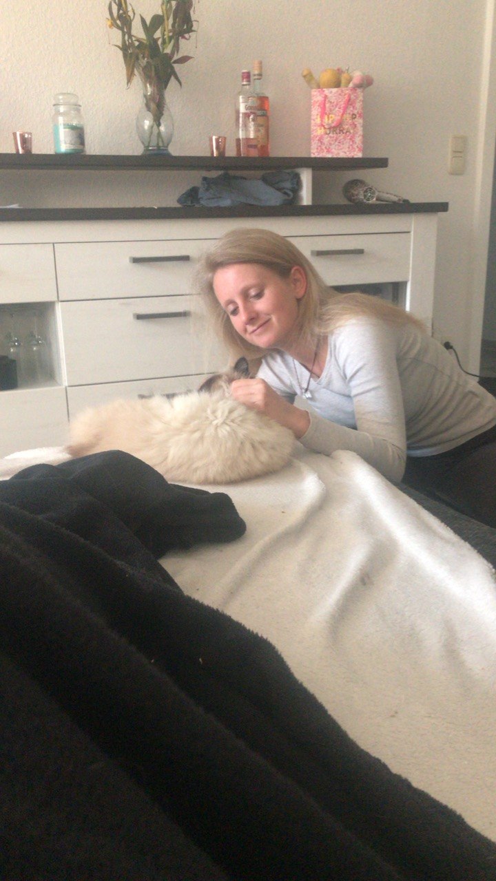 Lía acariciando a un gato blanco sobre una cama